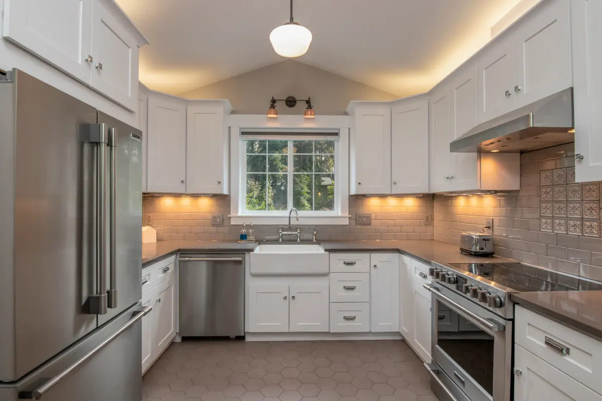 Compact kitchen with white cabinets and a window over the sink