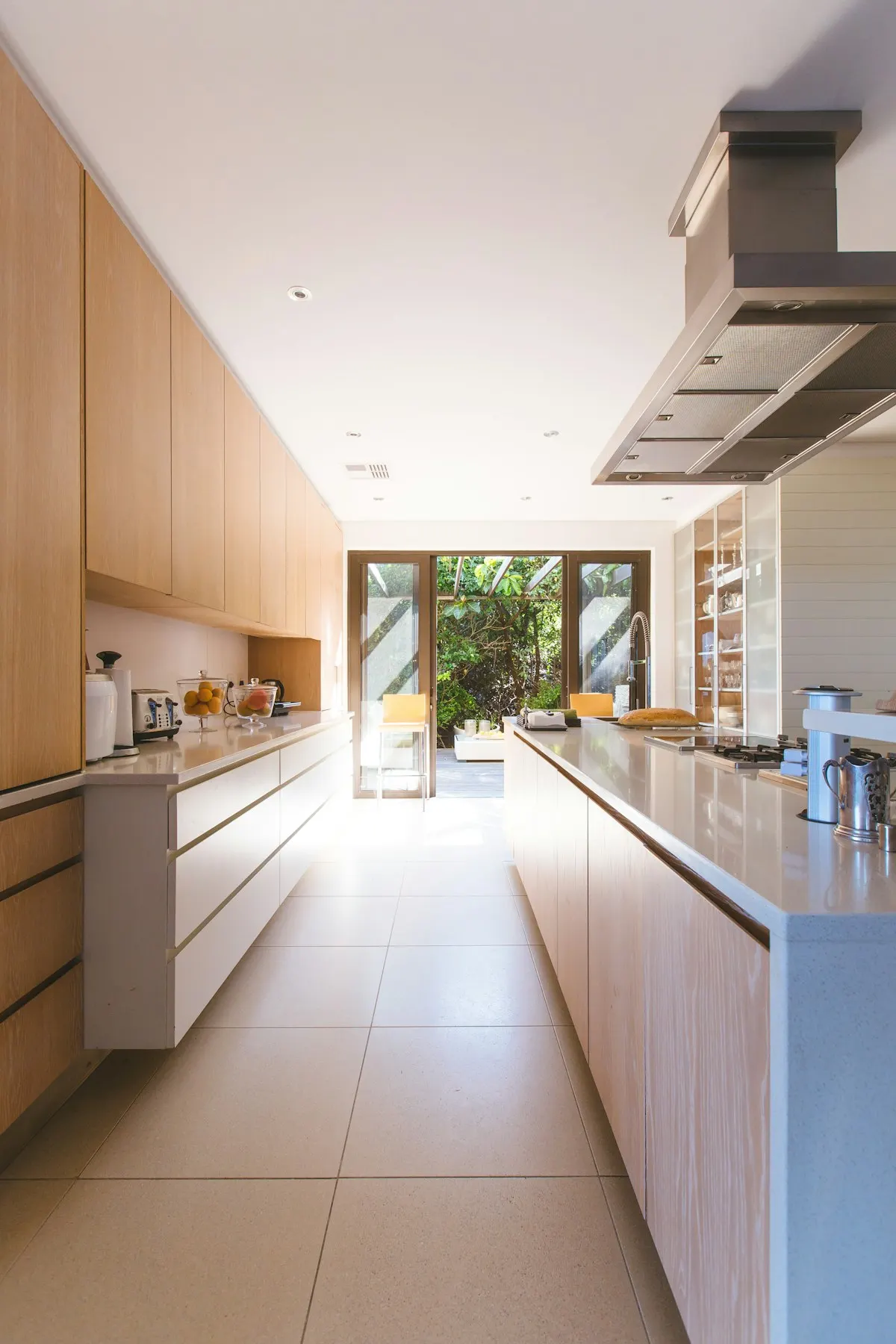 Long kitchen opening onto a garden through glazed doors