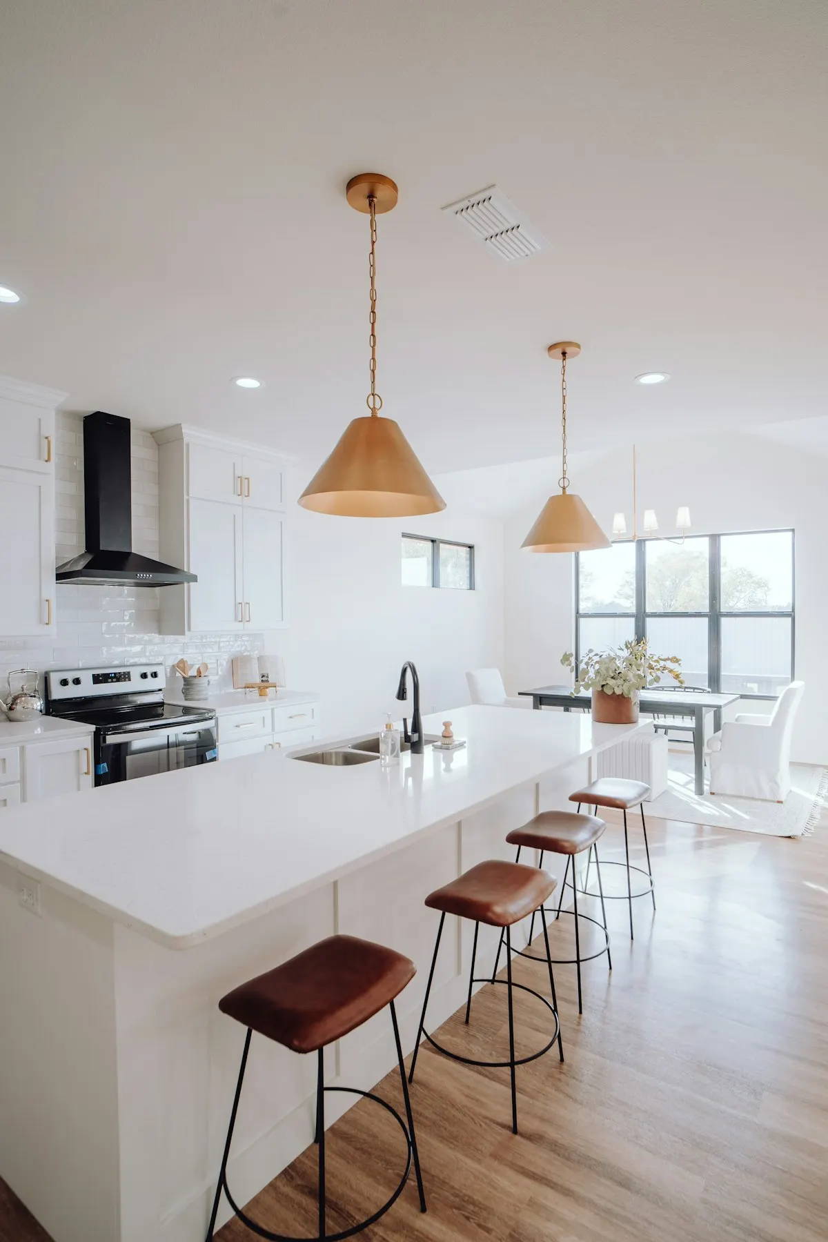 Kitchen island beside a dining area with timber pendant lights