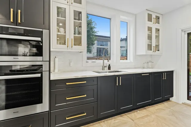 Dark base cabinets beneath windows and pale upper cupboards