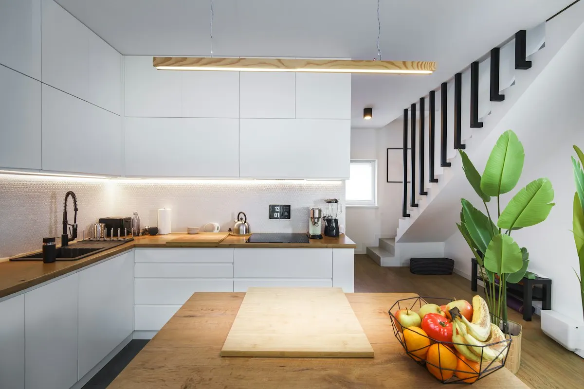 Kitchen with illuminated worktops beneath an open stair